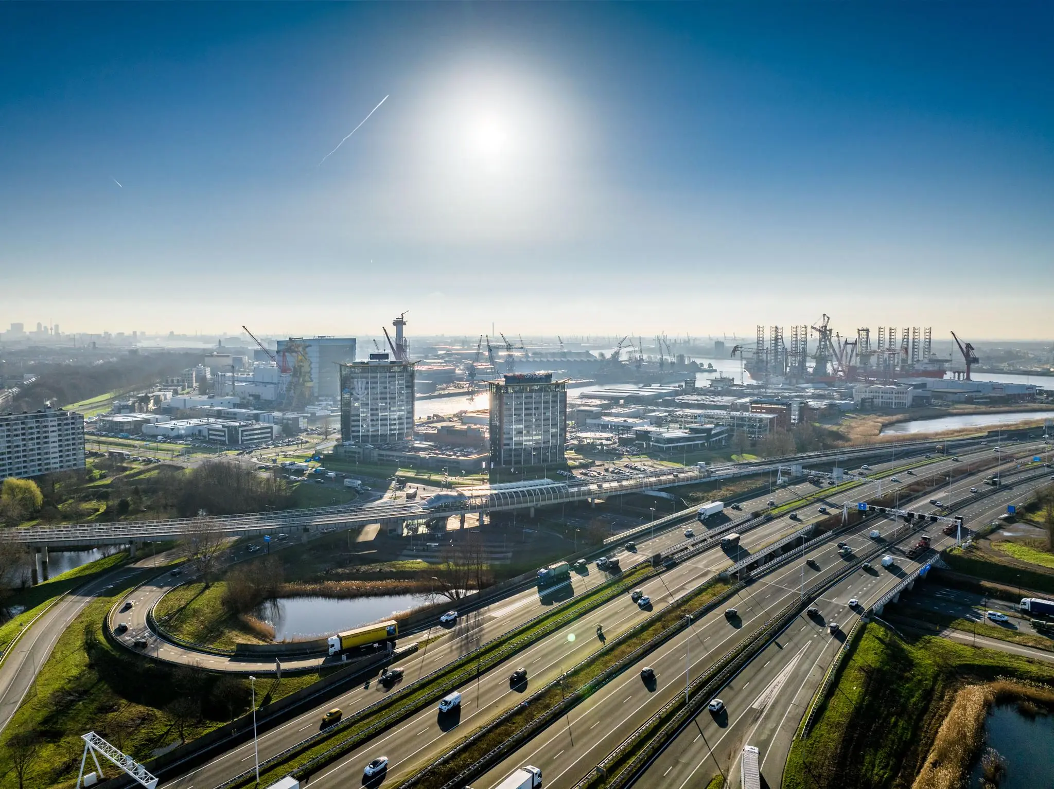 Luchtfoto van de Karel Doormanweg in Rotterdam met zicht op snelwegen, hoogbouw en de havenkranen op de achtergrond.